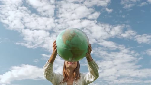 Woman Holding Globe Towards Sunny Sky