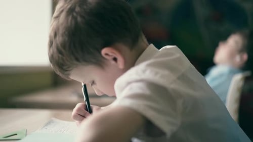 Child Concentrates on Writing at Desk
