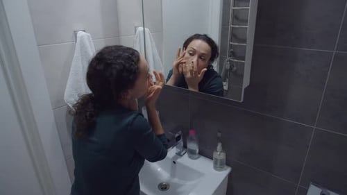 Charmante femme adulte vérifiant la peau du visage pour détecter les rides et l'acné en intérieur