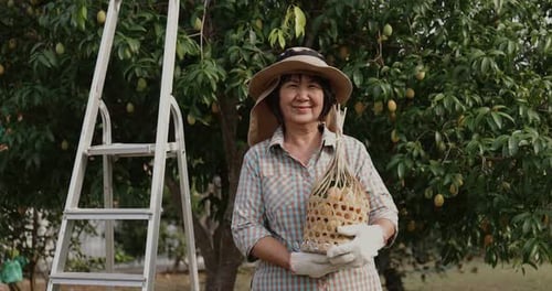 Happy Farmer Harvesting Fruit in Orchard
