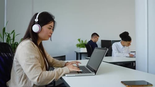 Mujer asiática que trabaja en una oficina de espacio abierto