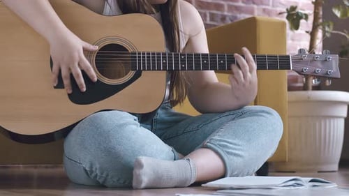 Woman Playing Guitar and Writing Music