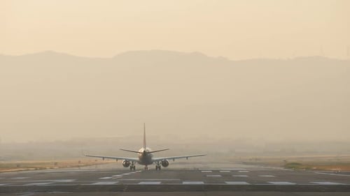 Airplane Taxis on Runway in Hazy Morning Light