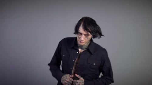 Tattooed Adult Unbuttons Black Shirt in Studio