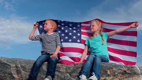 Children Holding American Flag on Rock Against Blue Sky