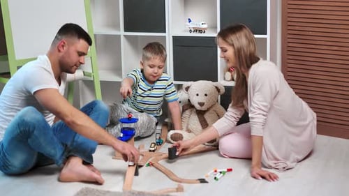 Smiling Mother and Father Playing with Cute Son in Toy Car Road at Cosiness Children Room