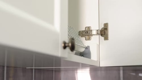 A Man Opens an Empty Kitchen Cupboard for Storing Dishes. Empty Cupboard in the Kitchen.