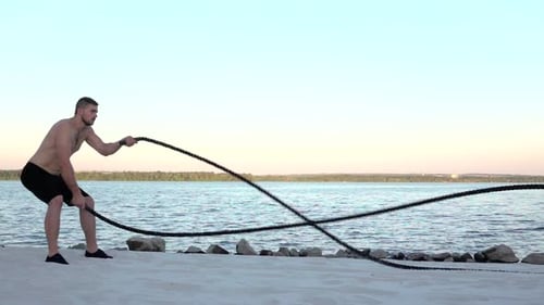 Der Sportler führt das Training mit den Seilen an der Sandküste durch. Zeitlupe