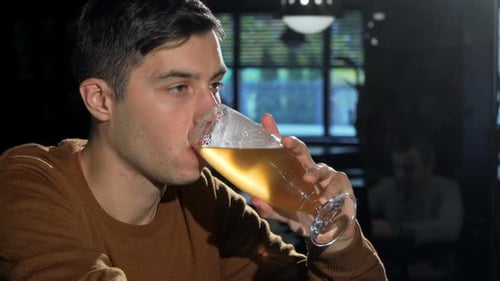 Man Sipping Beer From His Glass Relaxing at the Bar