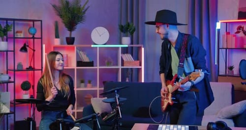 Groupe de musique composé d'un guitariste barbu et d'une batteuse aux cheveux longs tenant un essai