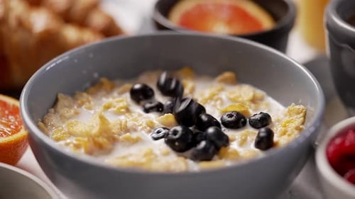 Blueberries Falling into Cereal with Milk for Breakfast