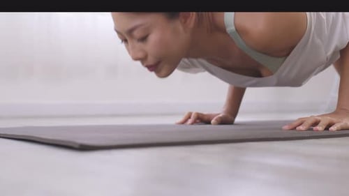 Posture de yoga debout, Vrischikasana sur tapis, femme asiatique en tenue de sport s'entraînant à l'intérieur.