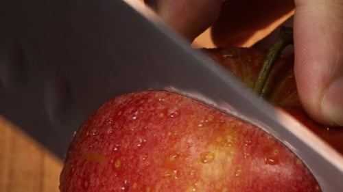 Sehr scharfes Messer schneidet eine Scheibe aus einem roten Apfel, Makroaufnahme. Detaillierte Nahaufnahme in 4K.