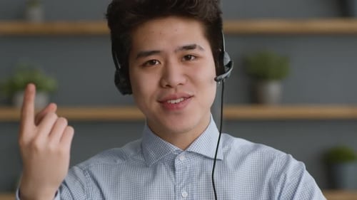 Porträt eines jungen selbstbewussten asiatischen Mannes mit Headset, der mit der Kamera spricht und die Grundlagen des Internets erklärt