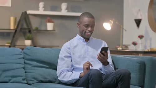 Young Adult Using Smartphone While Relaxing on Couch