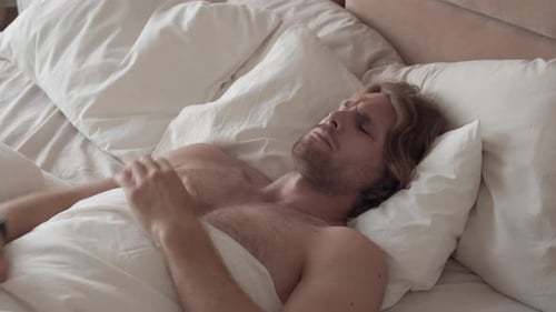 Man Wakes Up and Stretches in Bed