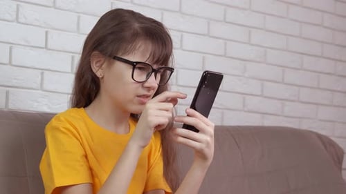 Girl Using Mobile Phone at Home on Couch