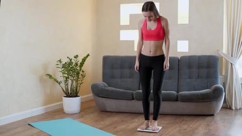 Distressed Woman in Sportswear Measures Her Weight on the Floor Scales