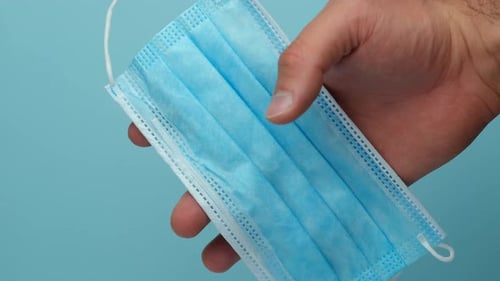 Hand Holds and Releases Light Blue Face Mask