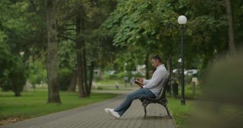 Ein junger Erwachsener mit Buch im Park