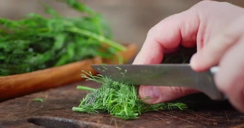 Men Hands Slice the Dill on a Cutting Board.