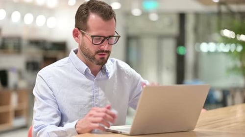 Stressed Businessman with Laptop Having Headache in Office