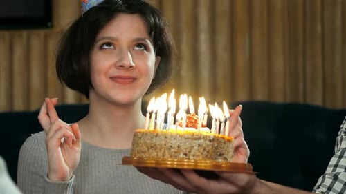 Young Woman Blows Out Birthday Cake Candles