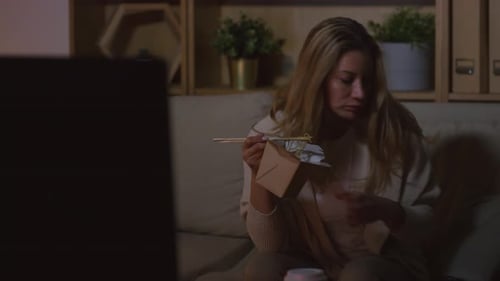 Woman Eating Noodles and Watching TV