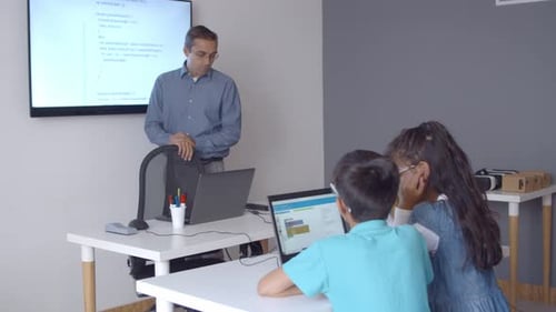 Teacher Helping Students with Coding in a Classroom