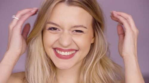 Blonde Woman Smiling and Touching Hair Close-up
