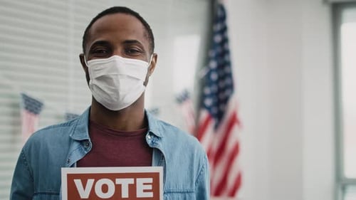 Person Holds Vote Sign near American Flags