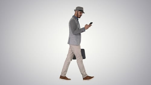 Hombre casual enviando mensajes de texto por teléfono y caminando sobre un fondo degradado.