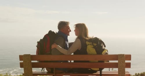 Active senior couple sitting on bench in forest