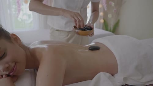 Jeune femme se faisant masser aux pierres chaudes au spa, relaxation et aromathérapie