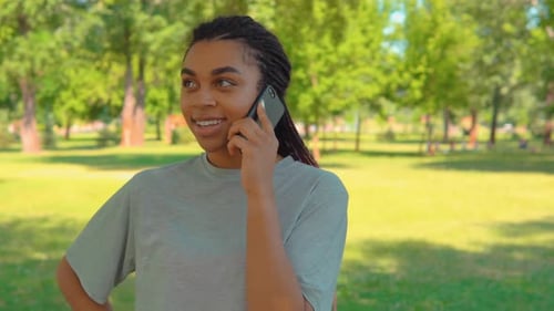 Cheerful Student Talking By Phone in City Park