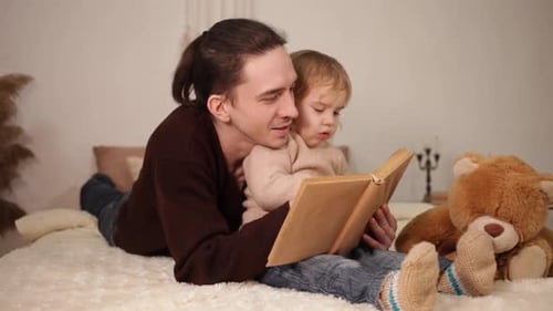 Man Reading Book To Child On Bed