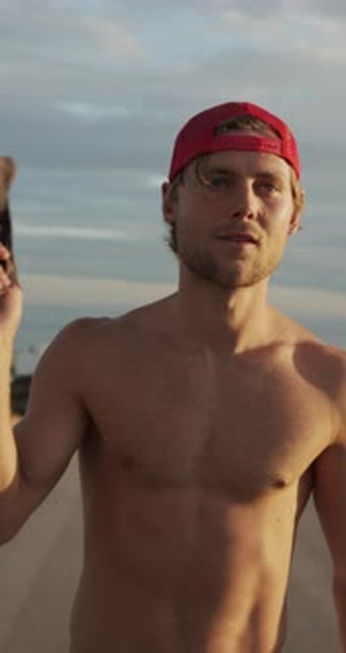 Shirtless Man Walking on Beach with Red Hat