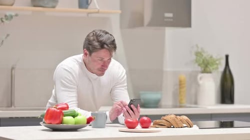 Man Using Smartphone in Modern Kitchen