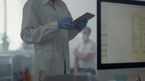 Medicine Worker Typing Patient Information on Tablet Standing Modern Office