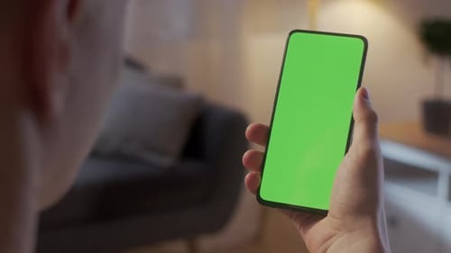 Back View of Man Holding Chroma Key Green Screen Smartphone Watching Content Without Touching or