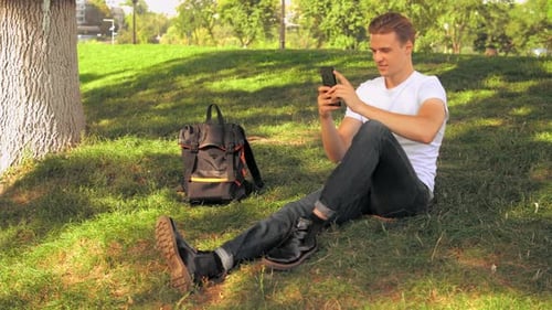 Man Using Smartphone While Sitting on Grass