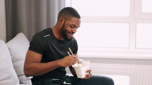 Man Enjoys Takeout Noodles at Home