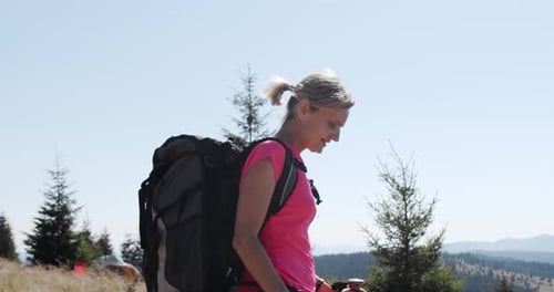 Woman Hikes With Backpack in Sunny Mountain