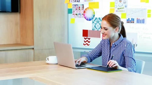 Woman Using Laptop and Stylus for Creative Work