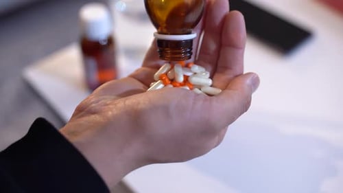 Pouring Orange and White Pills into Hand
