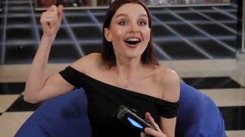 Woman Playing Video Game With Wireless Controller Indoors