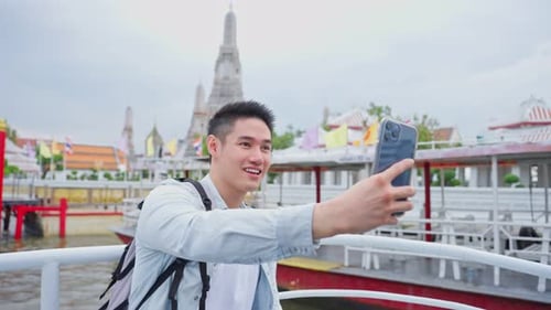 Asian man backpacker using mobile phone take picture of Buddha temple.