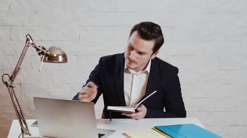 Professional Man Taking Notes at Desk