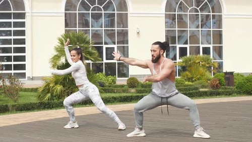 Sporty Couple Are Stretching Together on Top of High Urban Building. They Are Sitting on Mats and