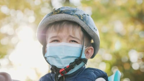 Little Boy Wearing a Bicycle Helmet and a Medical Mask